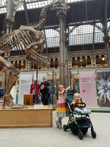 Toddler in Stroller and child in front of Iguandon skeleton at the museum of natural history in Oxford