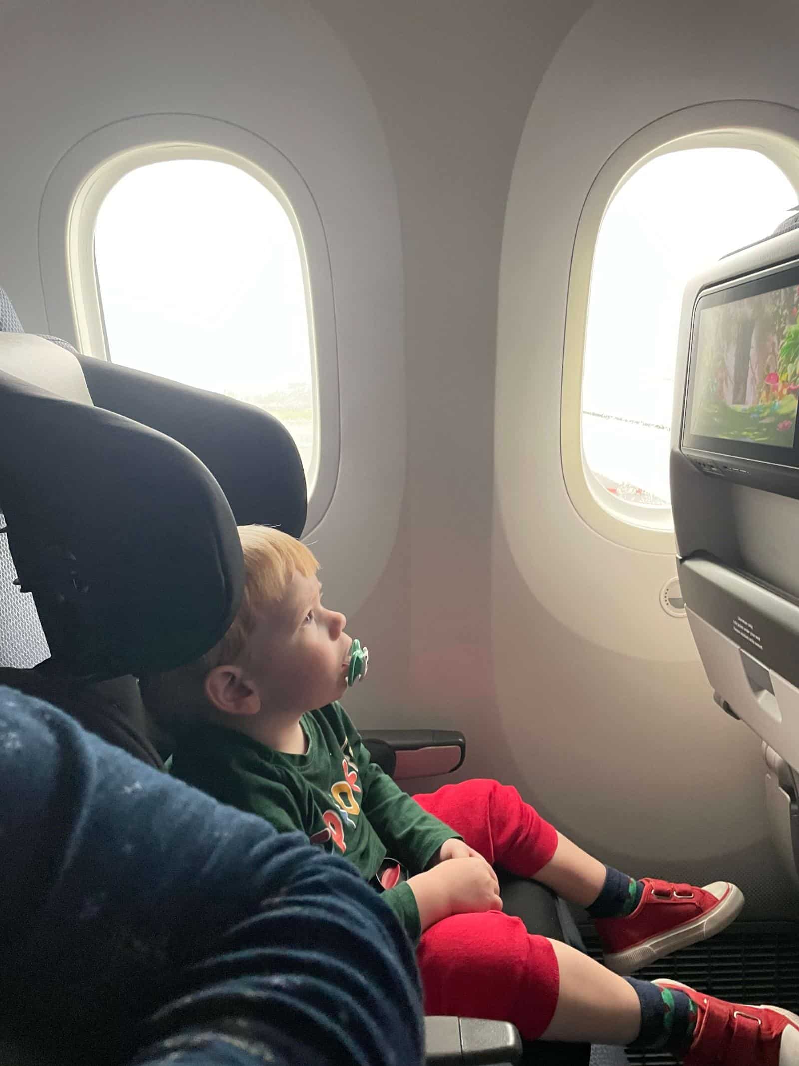 Toddler sat in car seat in an airplane seat