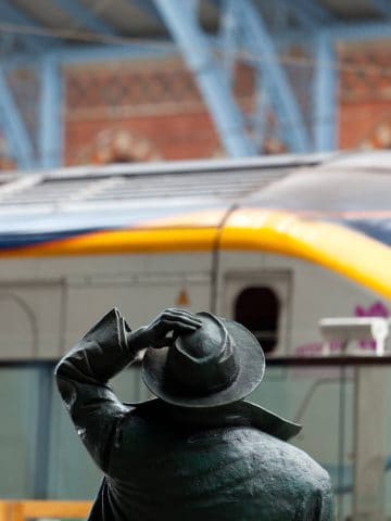 Back of the statue of Sir John Betjemen with a Eurostar train in the background